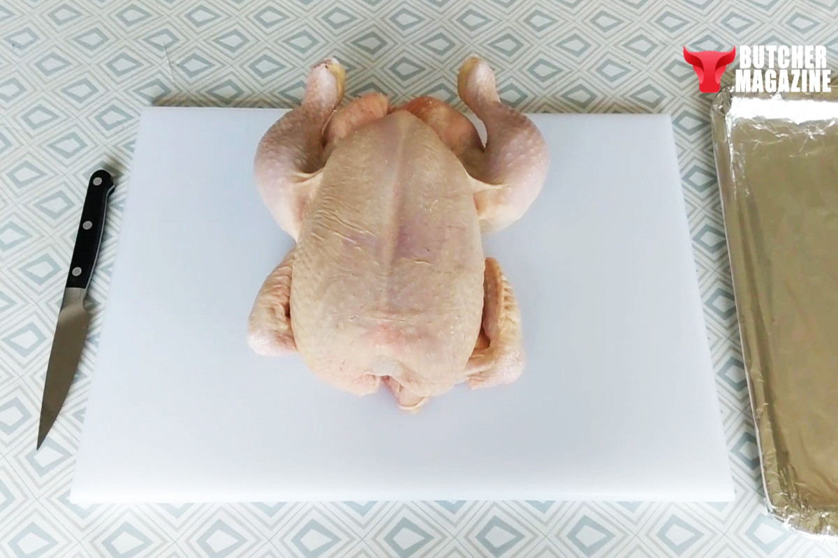 Using kitchen knife to cut raw chicken leg away from flesh