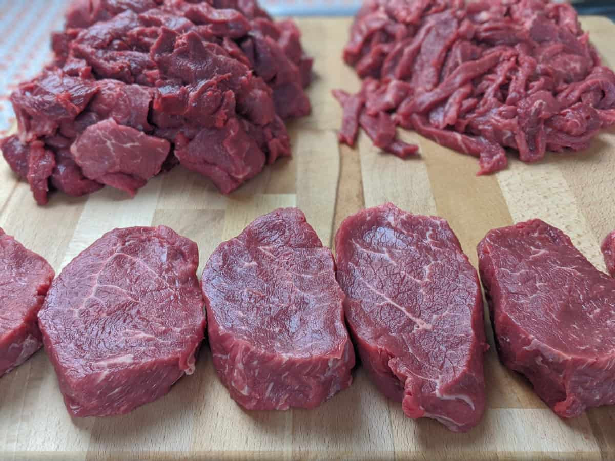 steaks and strips of beef on cutting board