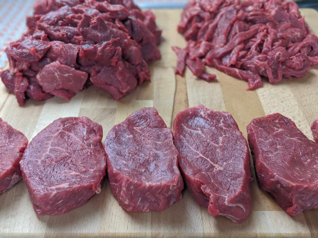 steaks and strips of beef on cutting board